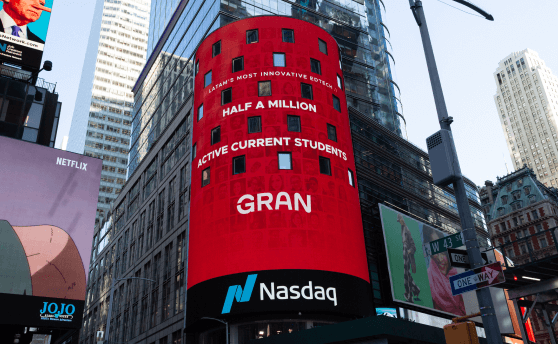 Grande painel iluminado da empresa Nasdaq exibindo a mensagem que a Gran atingiu o marco de 500.000 alunos ativos.