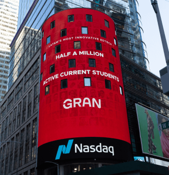Grande painel iluminado da empresa Nasdaq exibindo a mensagem que a Gran atingiu o marco de 500.000 alunos ativos.